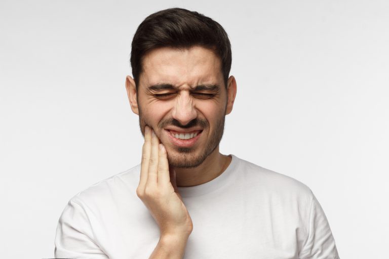 Man holding jaw with tooth pain due to cracked tooth